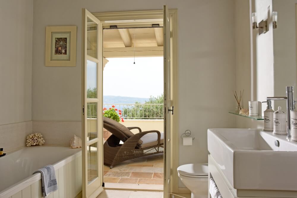 Bathroom at Villa Eremia with arched window opening to olive grove and sea views, Corfu