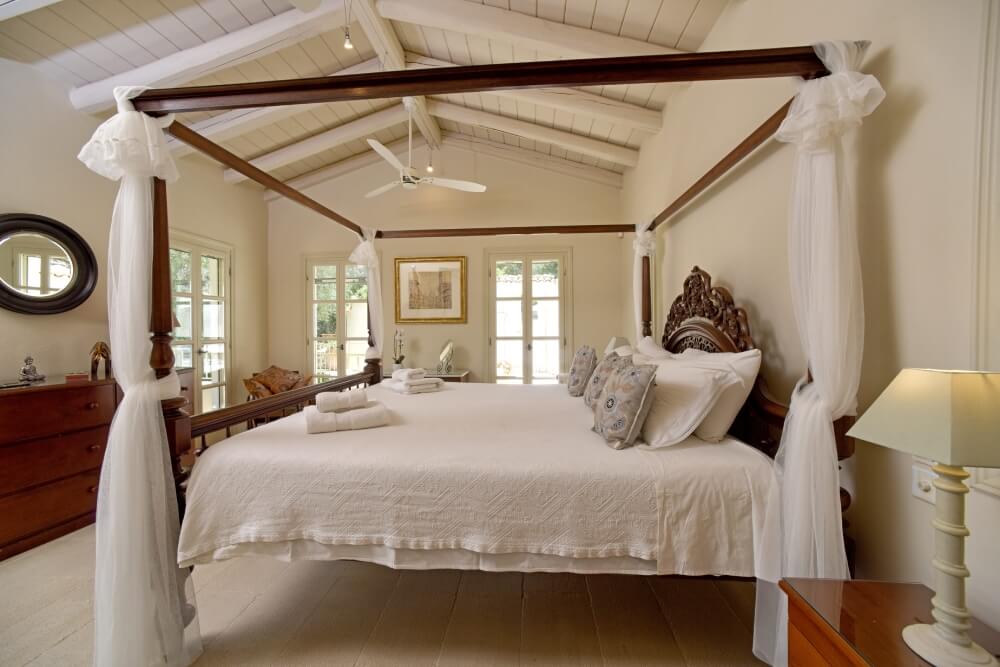 Spacious guest bedroom at Villa Eremia featuring a traditional dark wood four-poster bed