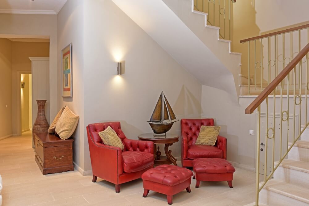 Stylish living space at Villa Eremia with a bold red armchair and natural stone wall detail