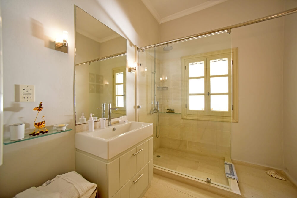 Master en-suite bathroom at Villa Eremia with arched window, bathtub and walk-in shower