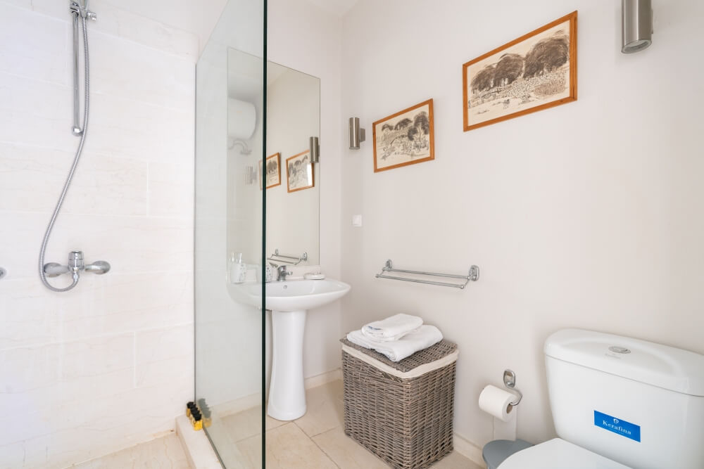 En-suite bathroom at Elyonas Cottage with rainfall shower, fresh towels and framed artwork