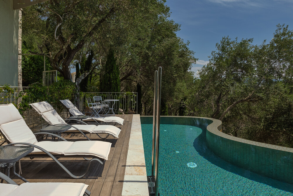 Pool deck at Elyonas Cottage with sun loungers beside the Indonesian-inspired tiled pool, Corfu