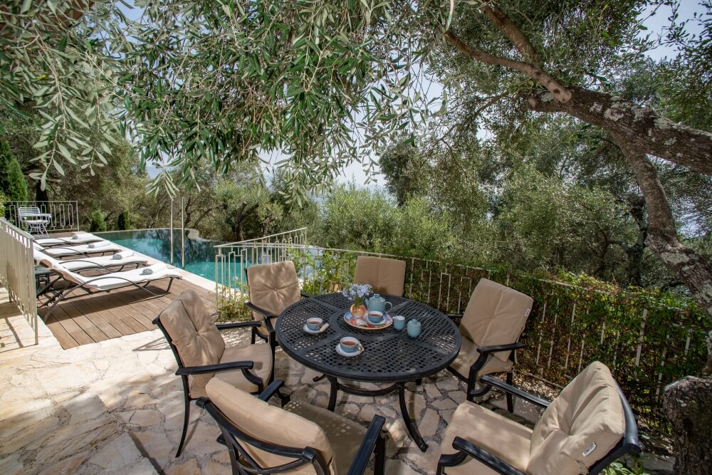 Outdoor dining area at Elyonas Cottage with wrought-iron table beside the private pool