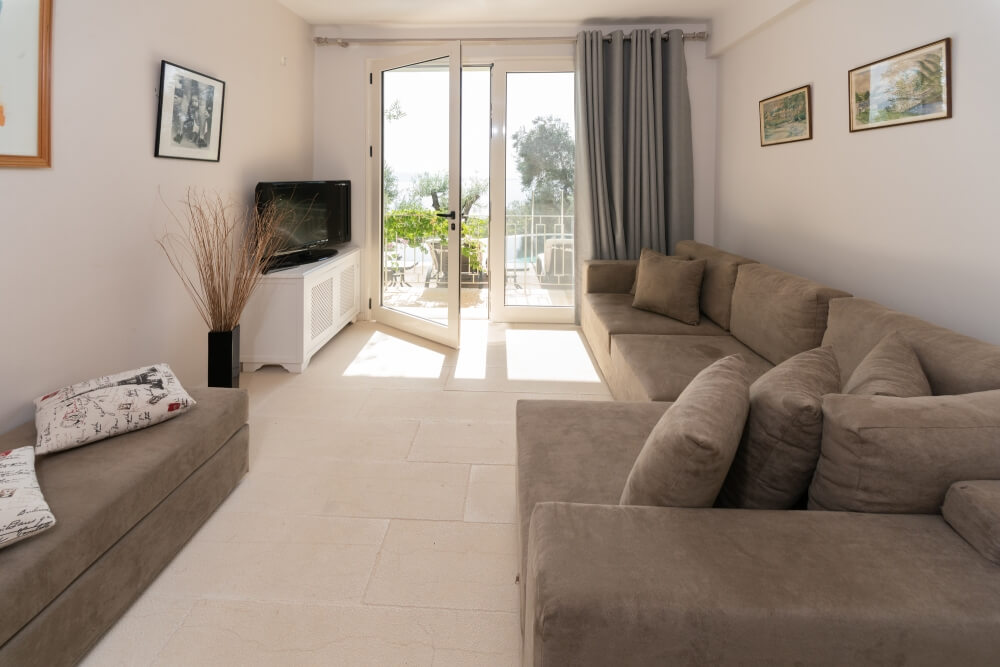 Sitting room at Elyonas Cottage with comfortable sofa, smart TV and doors to the sun deck